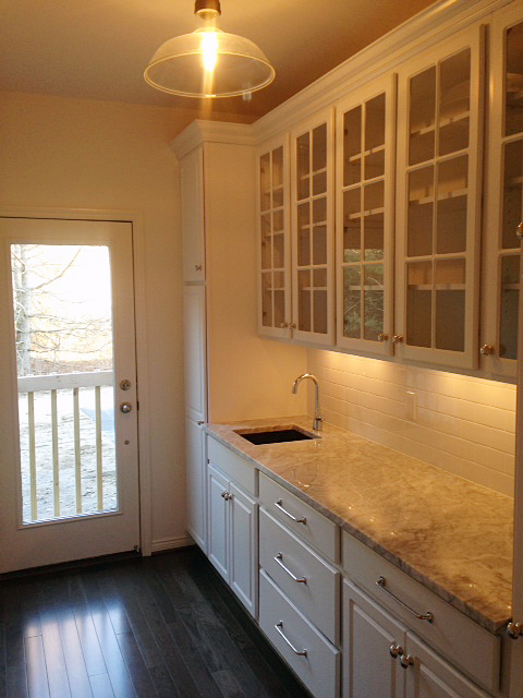 Butler pantry with sink and subway tile backsplash and indirect lighting under cabinets