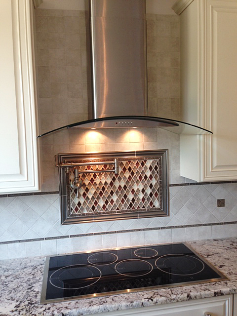 Cook top with tile back splash, pot filler, and stainless steel-glass hood vent