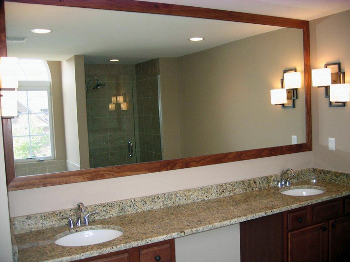 Dual sink bathroom with a stained framed mirror