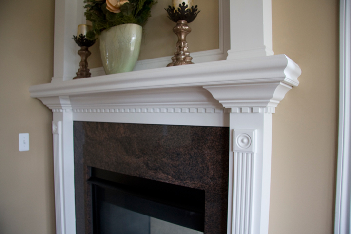 Fireplace surrounded in granite tile with white painted mantle