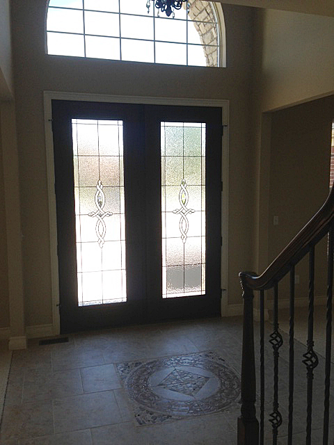 Foyer with frosted glass front door and medalion inlay on floor