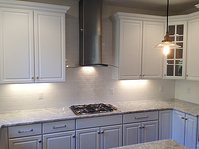Kitchen with white painted cabinets, granite counter tops, cook top and stainless steel range hood