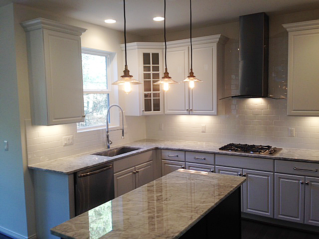 Kitchen with white painted cabinets, subway tile back splash and contrasting color island