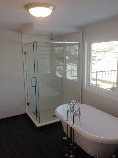 Master bath with free standing tub next to shower with euro style door