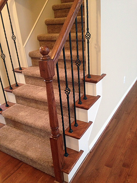 Staircase with oak end caps and rod iron basket spindles