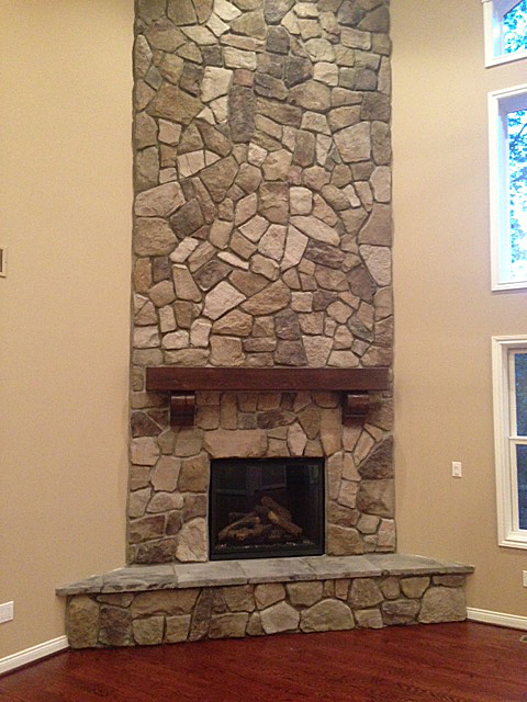 Two story stone fire place with wooden mantel