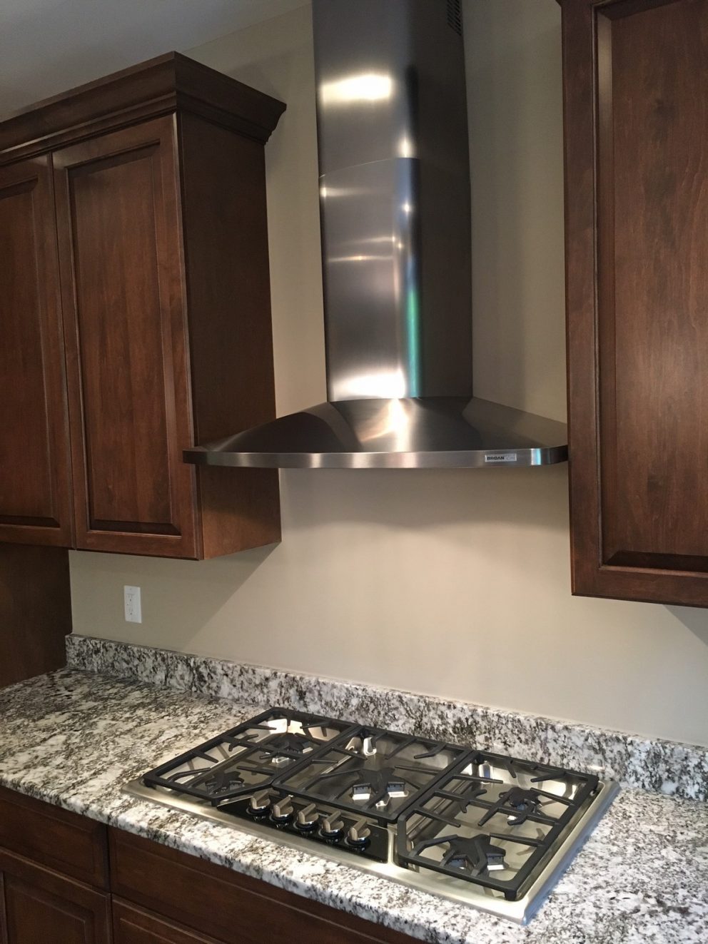 Gas cook top in granite counter top with stainless steel hood vent