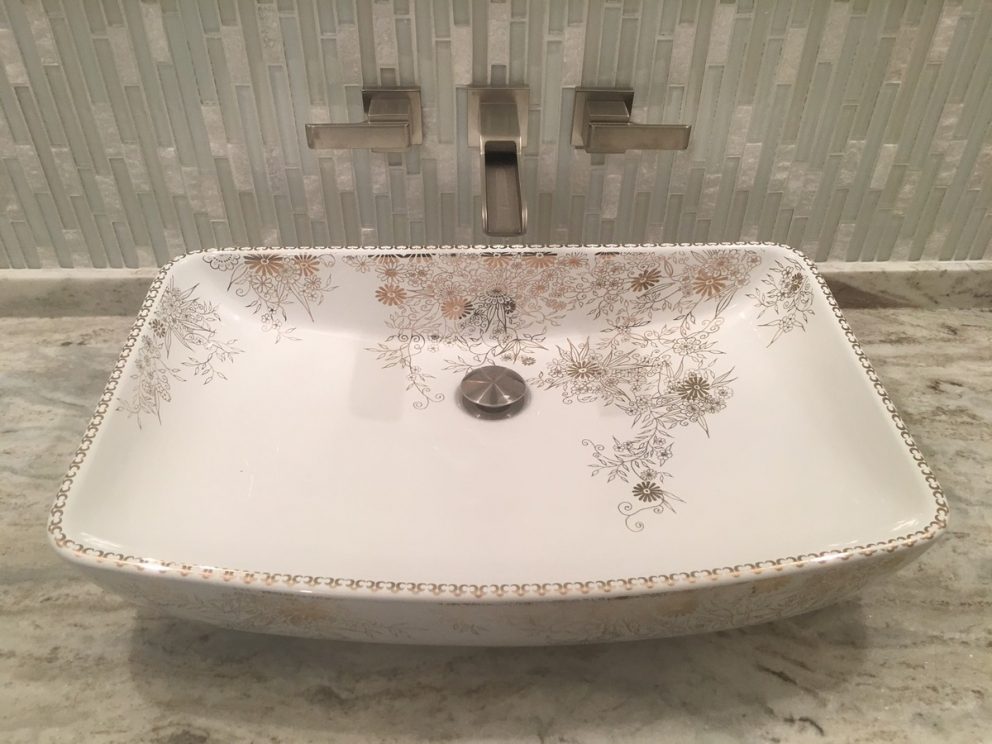 hand painted sink with faucet built into tile back wall