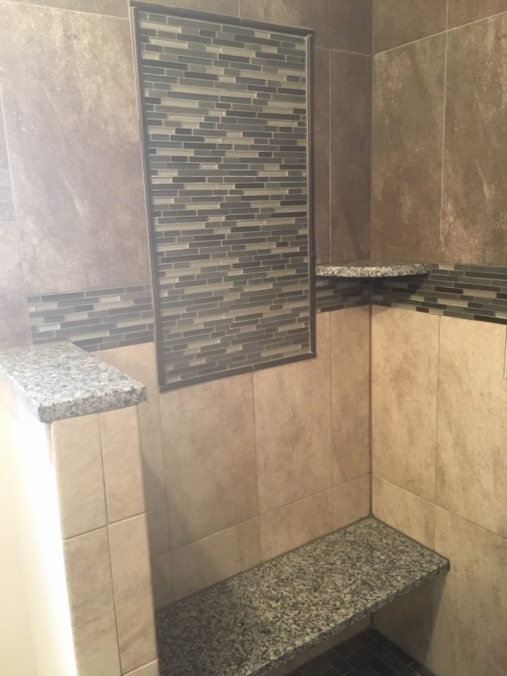 Master bath shower with custom granite bench and accent tiling