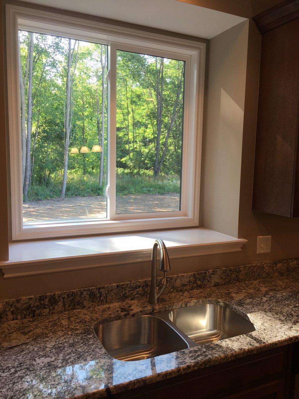 Stainless steel kitchen sink in granite counter top with bay window