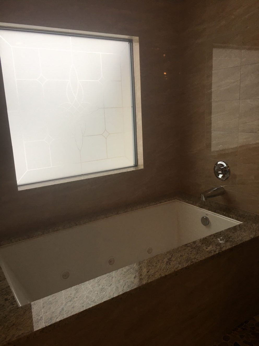 Undermount bathtub in master bath with frosted glass window